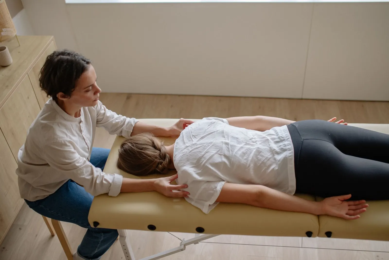 A chiropractor gently assessing the upper back of a patient lying face down