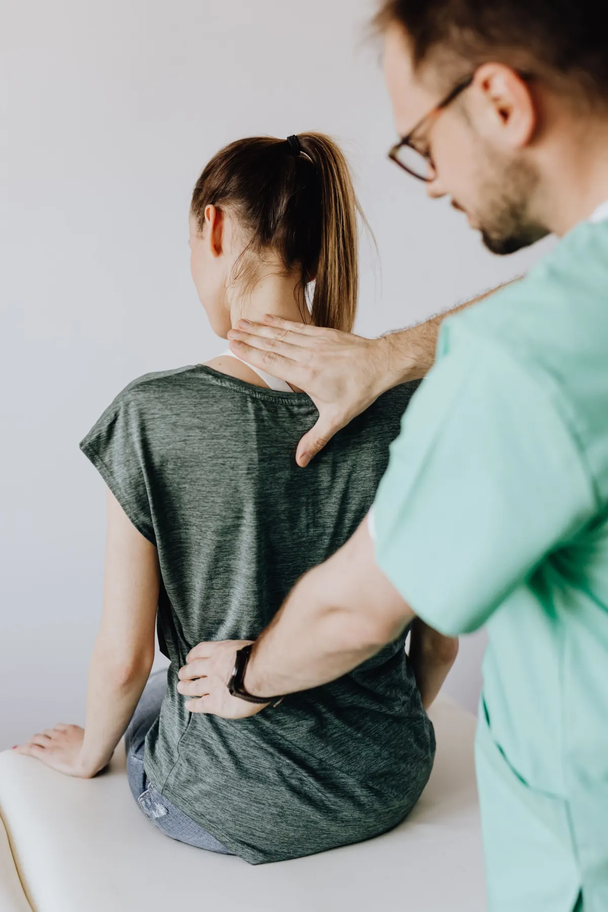 A chiropractor checking the lower back of a patient in the clinic
