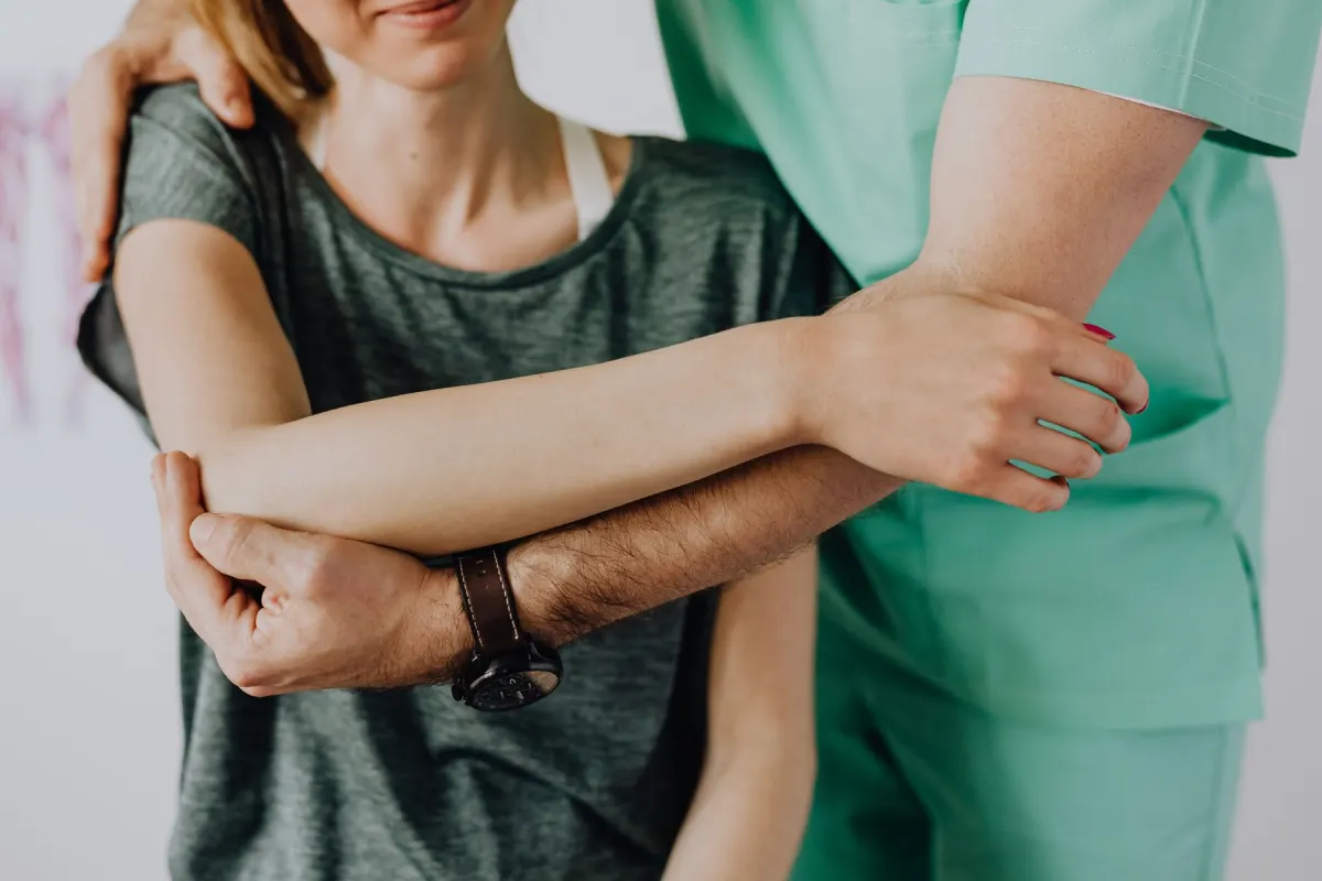 A chiropractor examining the shoulder of a patient in the clinic