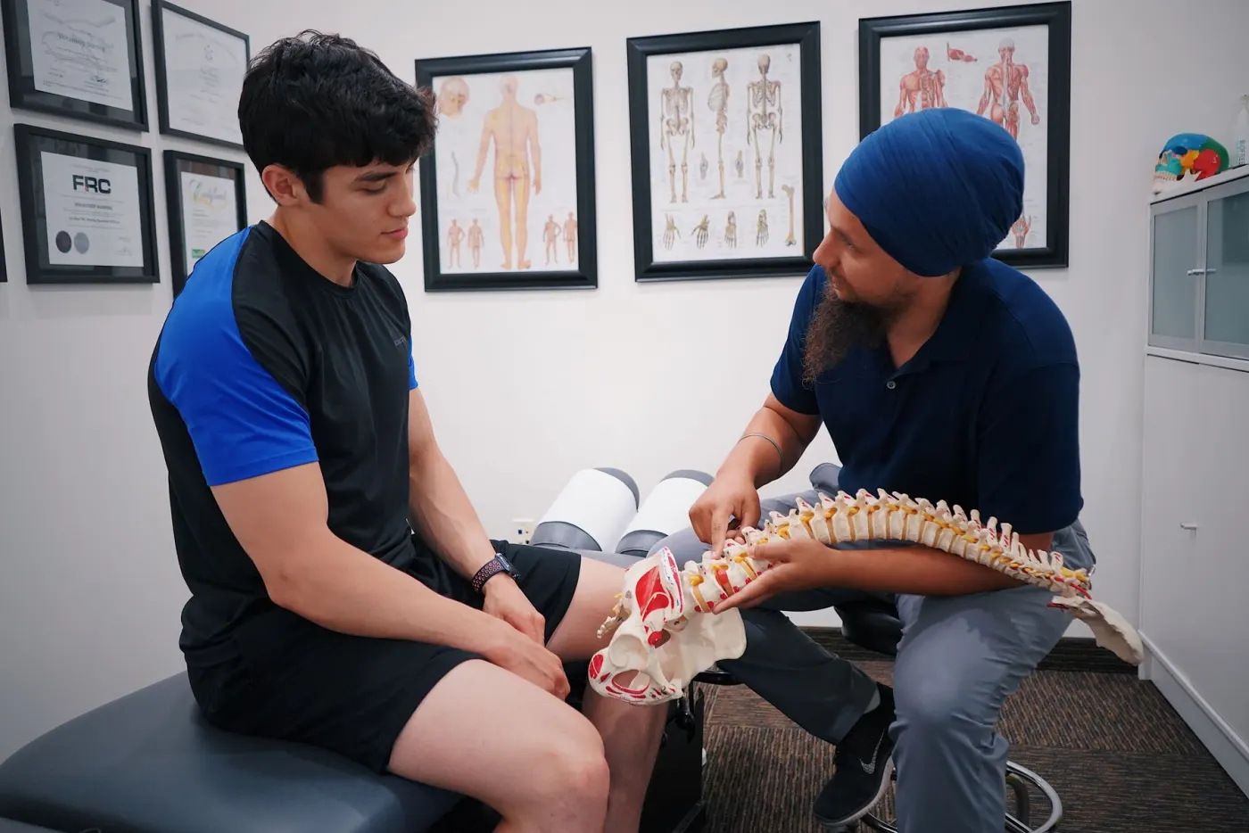A chiropractor explaining a spine model to a patient
